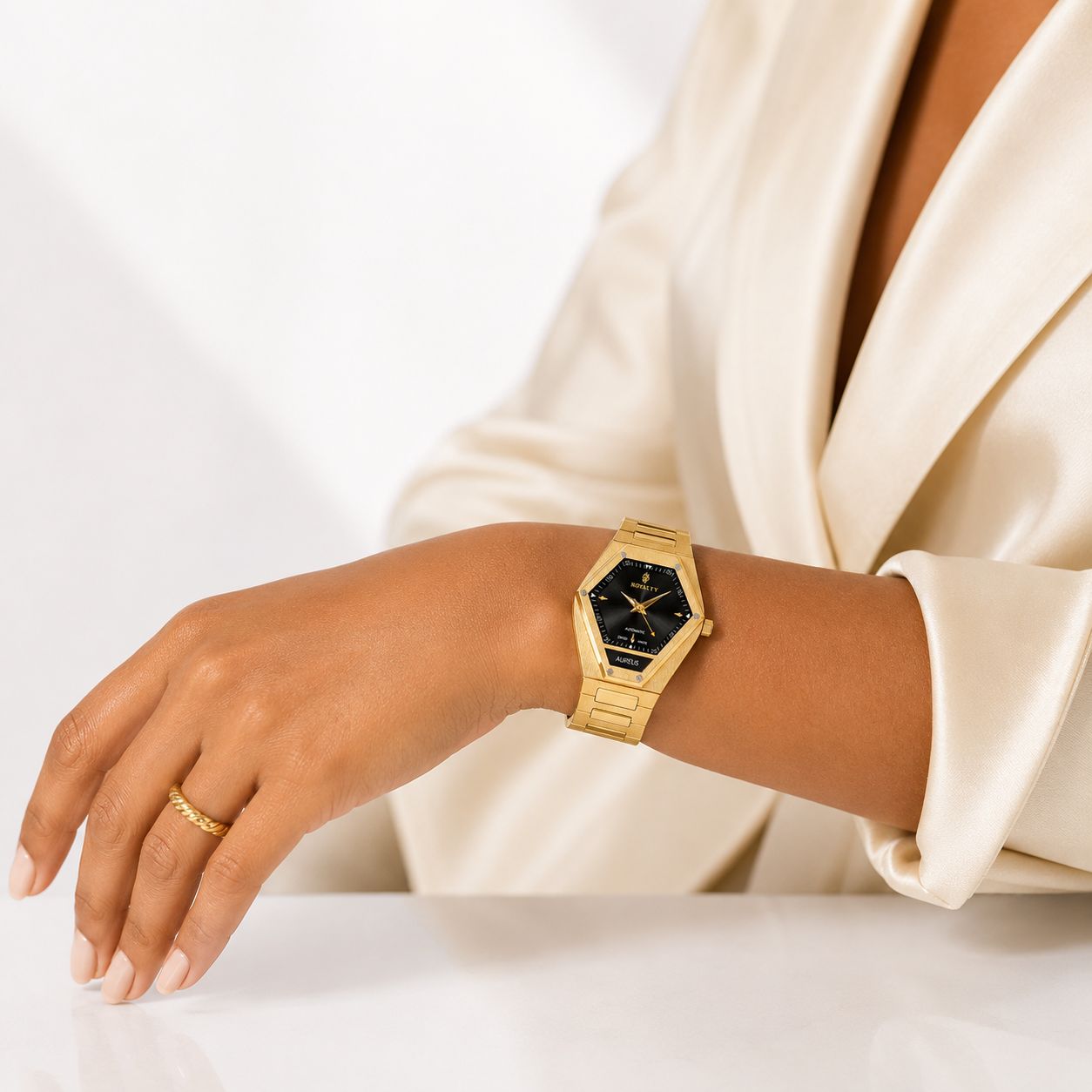 The Aureus on her wrist, against cream silk tailoring